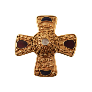 Decorative gold cross with red and black stones on a light gray background