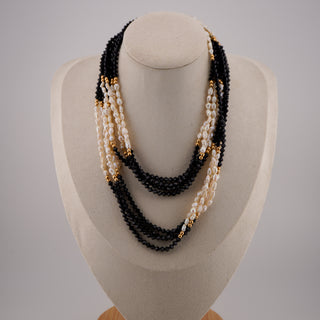 Necklace with black, white, and gold beads on a mannequin bust against a gray background