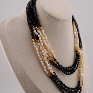 Necklace with black, gold, and white beads on a mannequin bust.