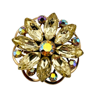 Gold brooch with clear gemstones on a white background
