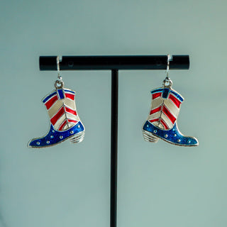 Cowboy boot earrings with Union Jack design on a black stand against a light blue background