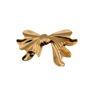 Gold bow-shaped brooch on a gray background