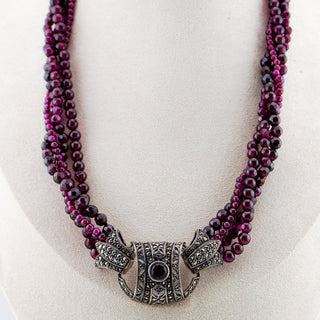 Necklace with purple beads and a decorative clasp on a mannequin bust.