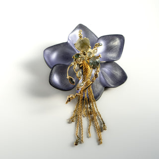 Decorative brooch with gold elements and purple flower-like design on a white background