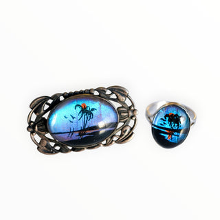 Brooch and ring set with palm tree design on a white background