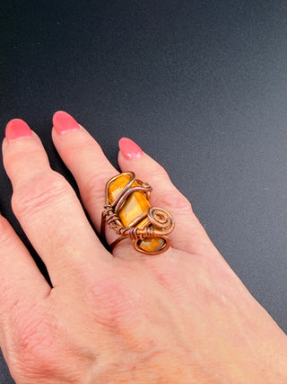 Hand wearing a ring with a yellow stone on a dark background