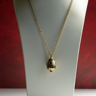 A vintage Joan Rivers egg-shaped pendant necklace with Roman numeral V design, adorned with clear rhinestones and black enameled details, attached to a gold-tone metal chain.