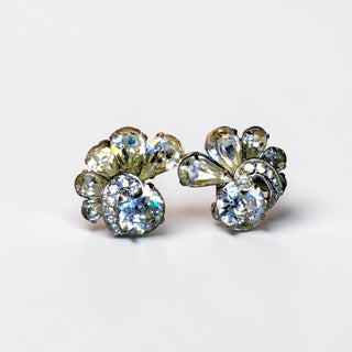 Pair of floral stud earrings with clear gemstones on a light gray background