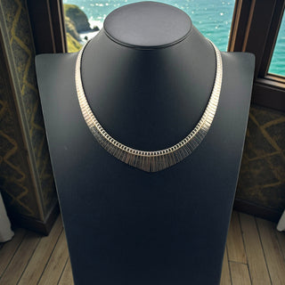 Silver necklace on a black mannequin with a scenic background