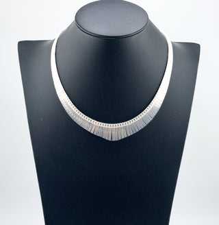 Silver necklace on a black mannequin bust against a white background