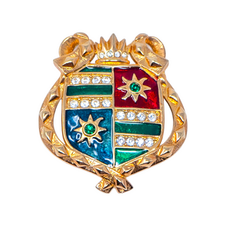 A gold-plated pin brooch featuring a shield or family crest motif with vibrant enamel colors and sparkling rhinestones.