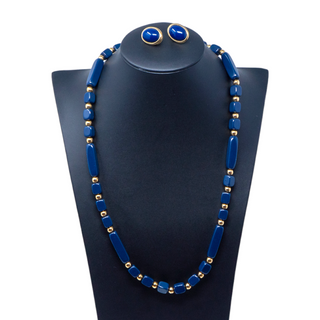 A vintage beaded necklace and earrings set with dark blue beads and gold-tone accents displayed on a mannequin bust