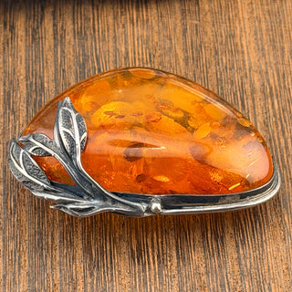 Amber stone with silver leaf design on a wooden background