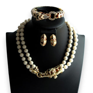 A vintage Ciner jewelry set featuring a gold-tone enamel rhinestone zebra clamper bracelet, a matching giraffe necklace with two strands of knotted faux pearls, and clip-on earrings displayed on a mannequin bust.