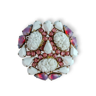 A vintage Hobe brooch with white carved flowers and pink and white stones set in a gold-tone metal frame.