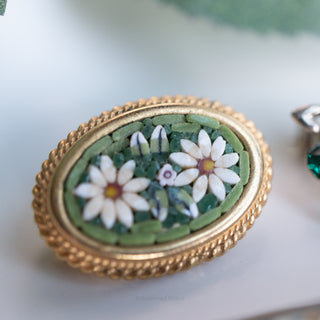Decorative brooch with floral design and gold frame on a light background