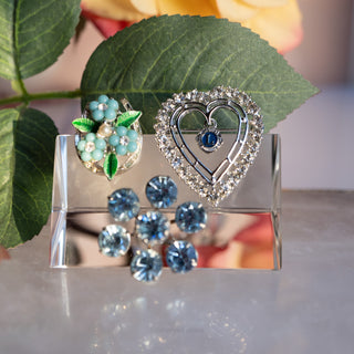 Set of earrings on a clear stand with green leaves in the background