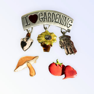 Brooch with 'I ❤️ Gardening' text and gardening-themed charms on a white background