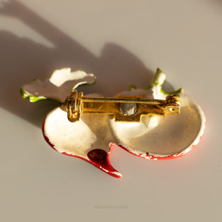 Gold and red brooch on a light background