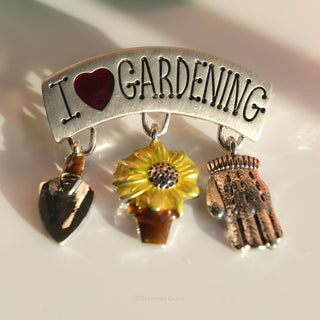 Brooch with 'I ❤️ Gardening' text and gardening-themed charms on a light background