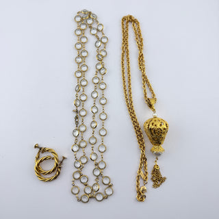 A vintage gold-toned jewelry set laid out on a white background, featuring a beaded chain necklace, a textured twisted toggle clasp, and a longer chain with a decorative hot air balloon pendant.