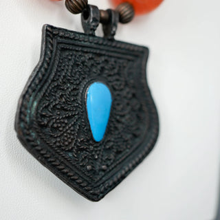 Reserved Grace vintage necklace featuring an ornate tribal metal pendant with a vibrant blue enamel teardrop accent.
