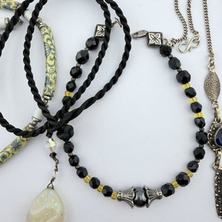 Reserved Grace artisanal jewelry set featuring black cord necklaces, patterned ceramic beads, and hematite accents.