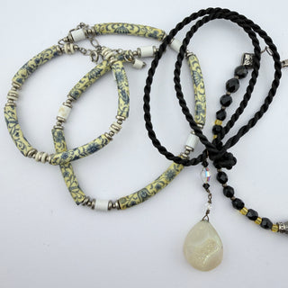 Reserved Grace artisanal jewelry set featuring floral ceramic beads, black cord, hematite, and a teardrop pendant.