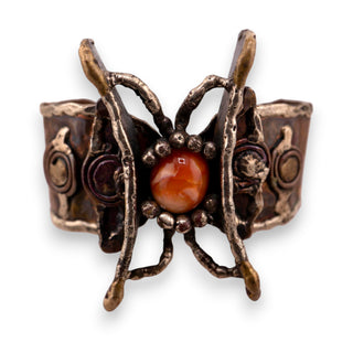 Reserved Grace handmade Brutalist cuff bracelet with a textured metal butterfly wing frame and orange glass stone.