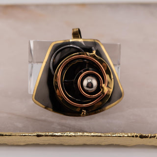 Reserved Grace brutalist pendant featuring layered bronze and copper spiral details on a dark metal base.