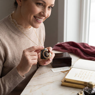 Reserved Grace brutalist mixed metal pendant with layered bronze and copper spiral details worn by a smiling woman.