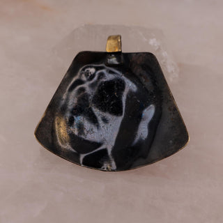 Reserved Grace brutalist mixed metal pendant featuring layered bronze and copper spiral details on a quartz surface.