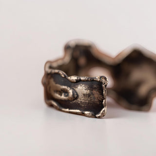 Reserved Grace artisan brutalist cuff bracelet in silver tone metal with textured edges resting on a quartz crystal.