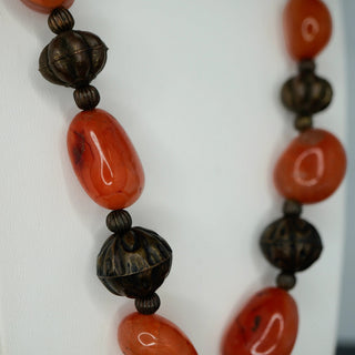 Reserved Grace vintage necklace with polished orange carnelian beads and dark metal spacer beads on a white display