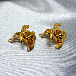 Reserved Grace vintage Chanel gold-plated CC turn lock clip-on earrings on a white satin background.