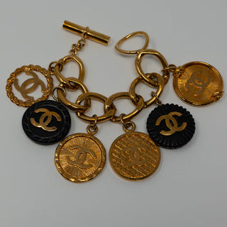 Reserved Grace vintage Chanel gold-plated charm bracelet featuring CC logo coin medallions and black resin accents.
