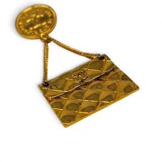 Reserved Grace vintage Chanel gold-plated brooch featuring a 31 Rue Cambon coin and a dangling quilted handbag charm.