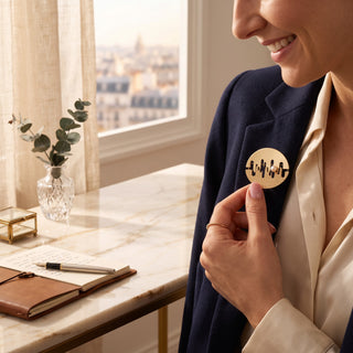 Reserved Grace gold tone abstract cut out brooch with mixed finish and pearl accent pinned to a navy blazer