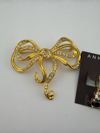 Reserved Grace gold-tone bow brooch with clear crystals and matching drop earrings on display