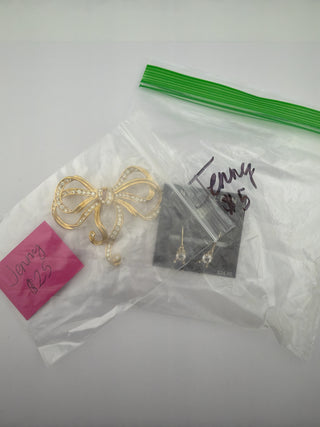 Reserved Grace jewelry set featuring a gold-tone crystal bow brooch and elegant drop earrings in plastic packaging.