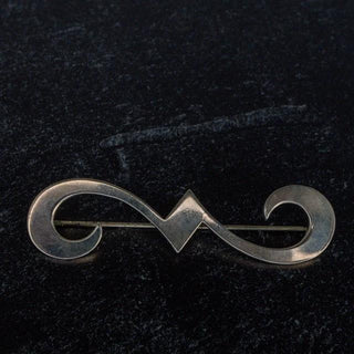 Reserved Grace James Avery sterling silver swirl brooch with a polished finish on a dark textured background.