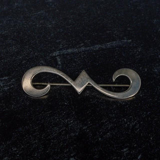 Reserved Grace James Avery sterling silver swirl brooch with a polished finish on a dark textured background