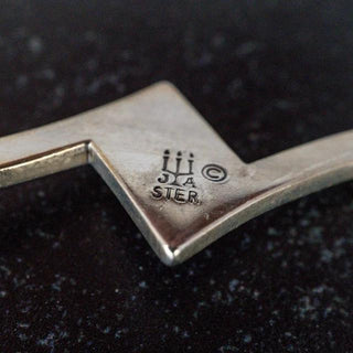 Reserved Grace James Avery sterling silver swirl brooch showing the hallmark stamp on a dark textured background
