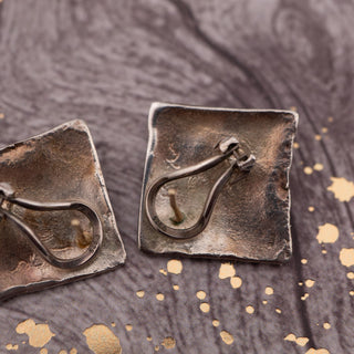 Reserved Grace sterling silver and gold abstract omega post earrings with secure lever backs on a textured surface