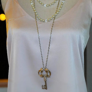 Reserved Grace vintage sterling silver Rococo key pendant on a long Italian 925 chain worn over a pale silk top.
