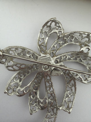 Reserved Grace vintage Trifari silver-tone filigree bow brooch showing the back pin mechanism and maker mark