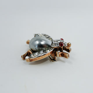 Reserved Grace vintage Trifari insect brooch with a silver-gray cabochon body, clear rhinestones, and red eyes.