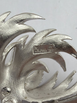Reserved Grace vintage Trifari silver-tone leaf brooch showing the signature hallmark stamp on brushed metal texture