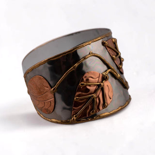 Reserved Grace Anju tri-tone cuff bracelet featuring silver, copper, and brass leaf appliqués on a wide metal band.