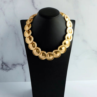 Reserved Grace vintage Monet necklace featuring matte gold-tone circular disks on a black display bust.